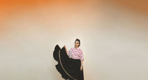 Woman dancing against orange wall