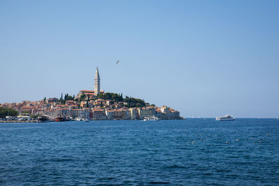 Sea by buildings against clear blue sky