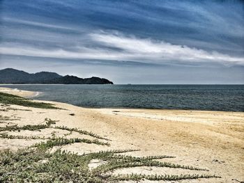 Scenic view of beach against cloudy sky