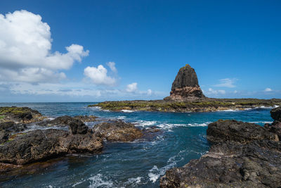 Rock formation on beach against blue sky