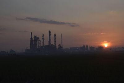 Silhouette of cranes against sky at sunset