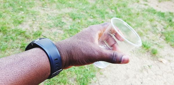 Midsection of man drinking glass on field