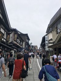 People walking on street in city against sky