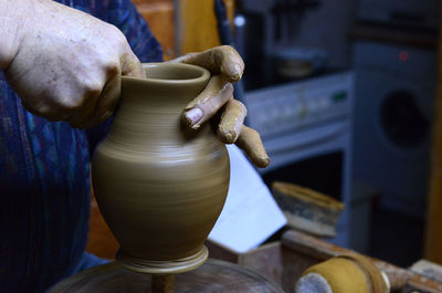 Craftsperson shaping pot on pottery wheel in workshop