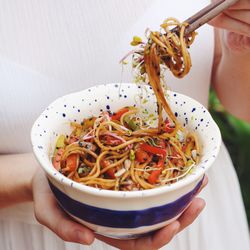 Midsection of woman holding noodles using chopsticks