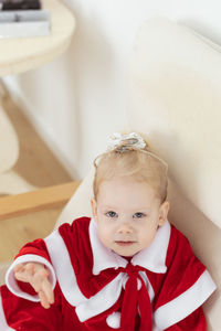 Portrait of cute girl sitting on sofa at home