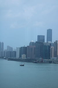 City buildings by sea against sky
