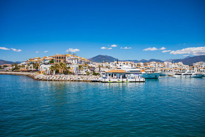 View of townscape by sea against blue sky