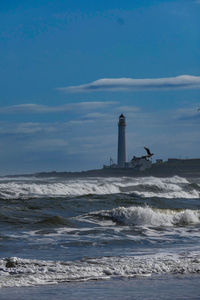 Lighthouse by sea against sky