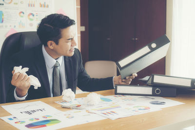 Angry businessman throwing paper balls in office