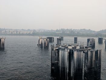 Wooden posts in sea against buildings in city