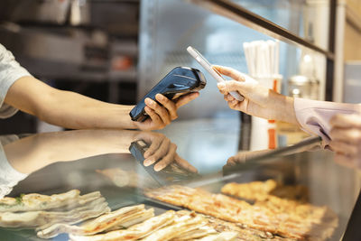 Hand of businesswoman making payment through smart phone on credit card reader