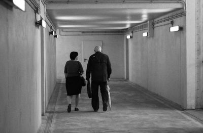 Rear view of men walking in illuminated building