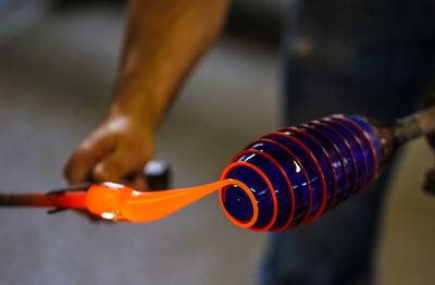 Manual worker holding glass blower in glass factory