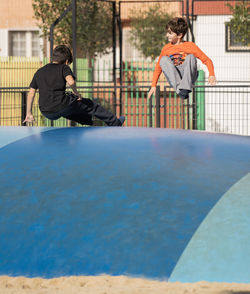 Two young boys enjoy jumping in inflatable air cushion bouncer playground.