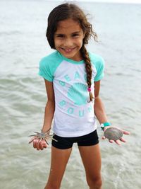 Portrait of smiling girl holding sea animals at beach
