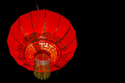 Low angle view of illuminated lantern against black background