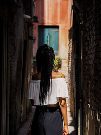 Rear view of woman standing in alley