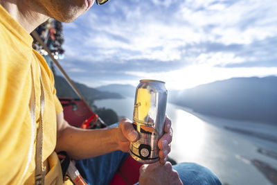 Man drinking and holding beer can at sunset on a portaledge squamish