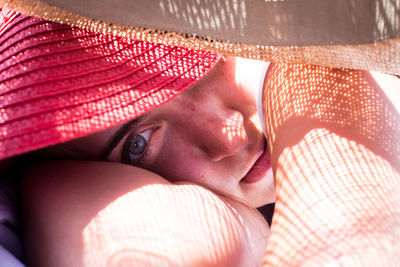 Close-up portrait of woman lying in hat