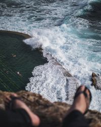 Low section of people standing on rocks at beach