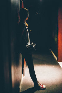 Full length of woman standing by wall at night