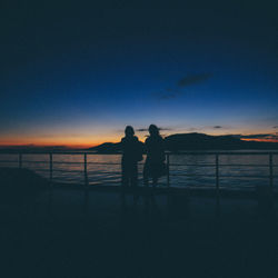Silhouette people standing on beach against sky during sunset
