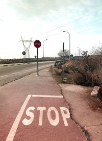 Road sign on street against sky