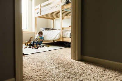 Boy playing with toys in bedroom seen through doorway