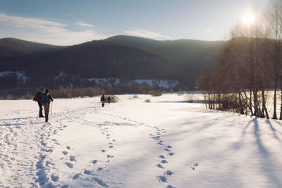 Rear view of people walking on snow covered land