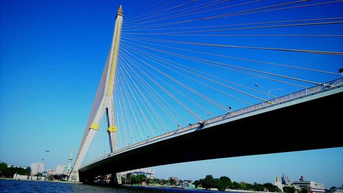 Low angle view of suspension bridge against blue sky