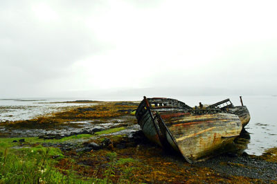 Abandoned boat on beach against sky