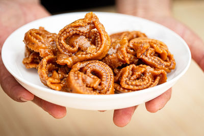 Hands serving a plate of chebakia a moroccan pastry - moroccan cookie  associated with ramadan