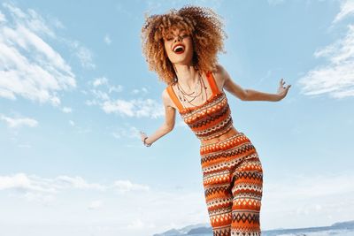 Portrait of young woman standing against sky