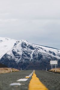 Road leading towards snowcapped mountain against sky