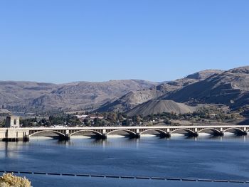 Bridge over river against clear blue sky