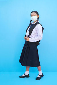 Full length of girl standing against blue background