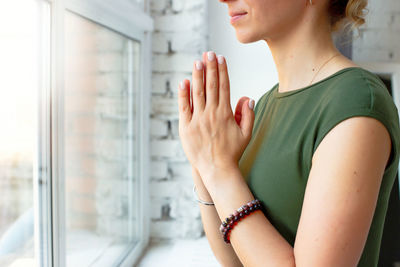 Girls in a green t-shirt, in a yoga pose close-up, folded their palms together on their chest