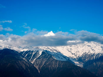 Scenic view of snowcapped mountains against blue sky