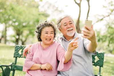 Portrait of a smiling young woman using mobile phone in park