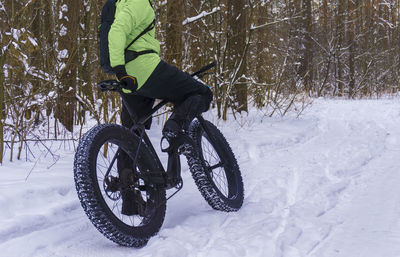 Low section of man cycling on snow covered land