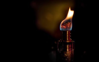 Close-up of lit candle against black background