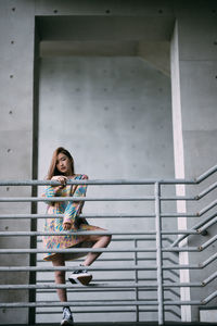 Portrait of young woman standing against wall