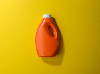 Close-up of yellow bottle against orange background