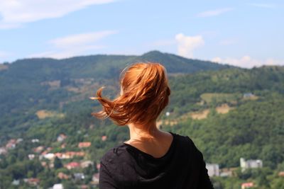 Rear view of woman looking at mountains against sky