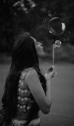 Side view of woman holding bubbles