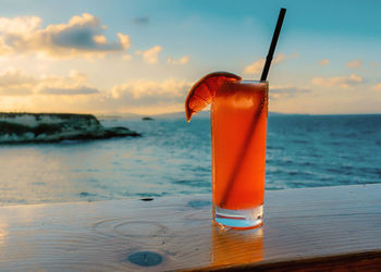 Close-up of drink on table at beach against sky