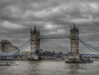 View of suspension bridge over river against cloudy sky