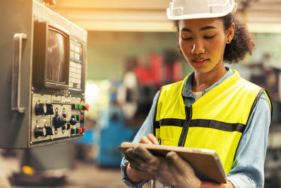 Standing in front of a control panel, a female industrial electrical engineer with a safety .