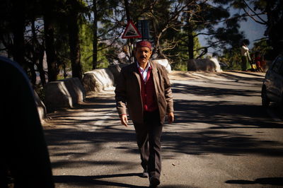 Full length portrait of young man standing on footpath in city